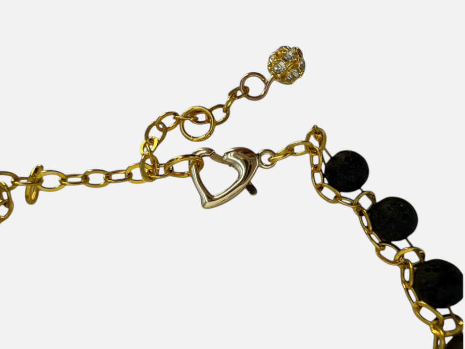 SPARQ armband met zwarte lavastenen, goudkleurige schakelketting, hartvormige sluiting en fonkelend bedeltje.