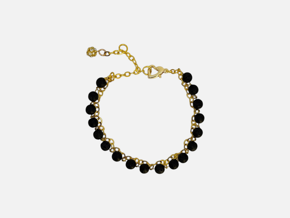 SPARQ armband met zwarte lavastenen en goudkleurige schakelketting, voorzien van hartsluiting en fonkelend bedeltje.