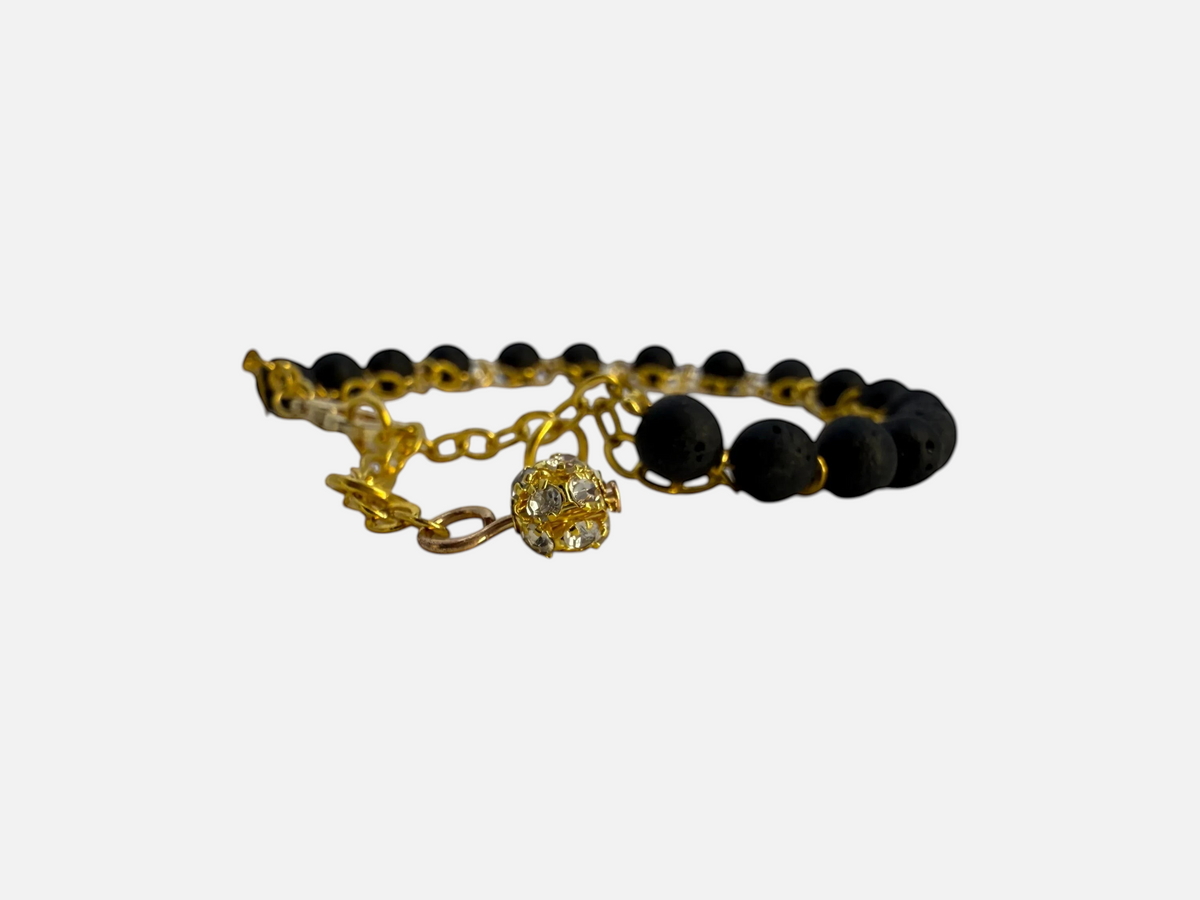 SPARQ armband met zwarte lavastenen, goudkleurige schakelketting en een sprankelende bedel met steentjes.