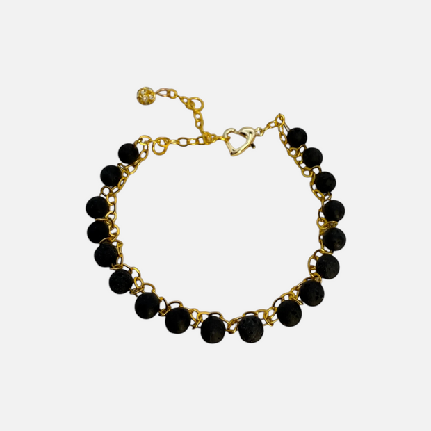 SPARQ armband met zwarte lavastenen en goudkleurige schakelketting, voorzien van hartvormige sluiting en bedeltje.