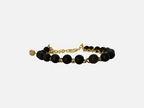 SPARQ armband met zwarte lavastenen en goudkleurige schakelketting, voorzien van een sprankelend bedeltje.