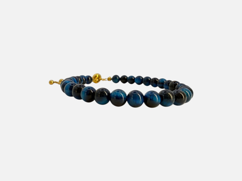 SPARQ verstelbare kralenarmband van blauwe tijgeroog met luxe goudkleurige details op een witte achtergrond.