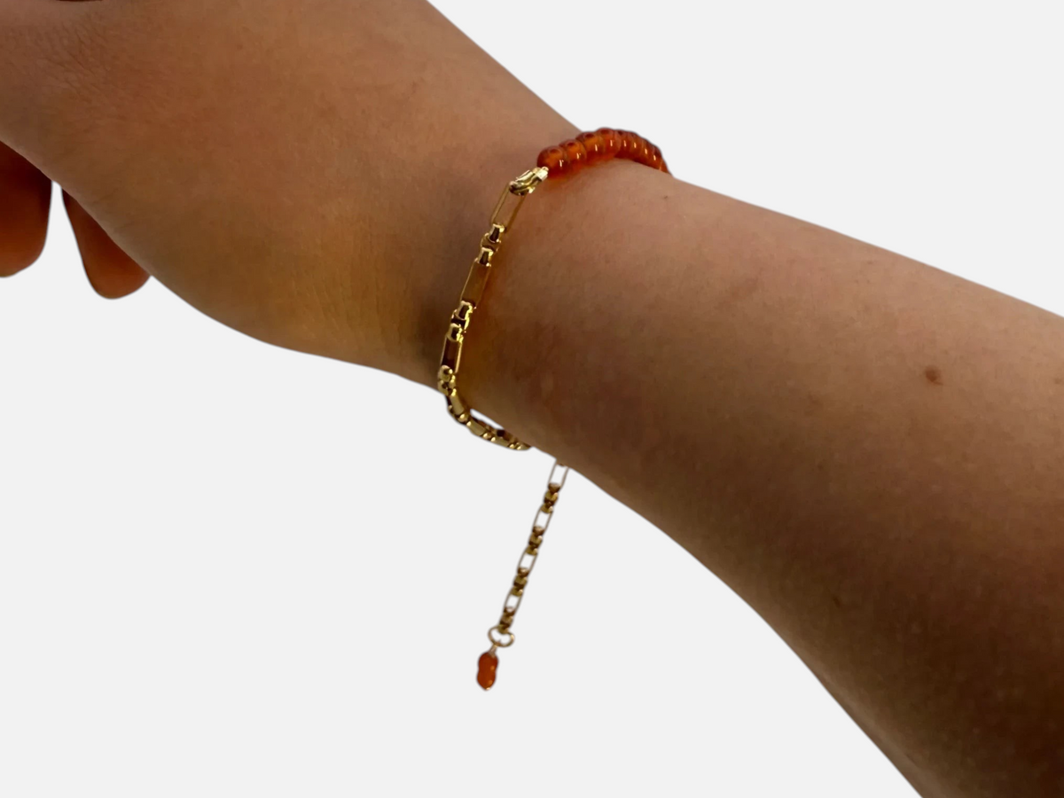 SPARQ armband met goudkleurige schakelketting en oranje edelsteenkralen om een pols