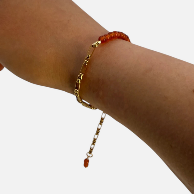 SPARQ armband met goudkleurige schakelketting en oranje edelsteenkralen om een pols