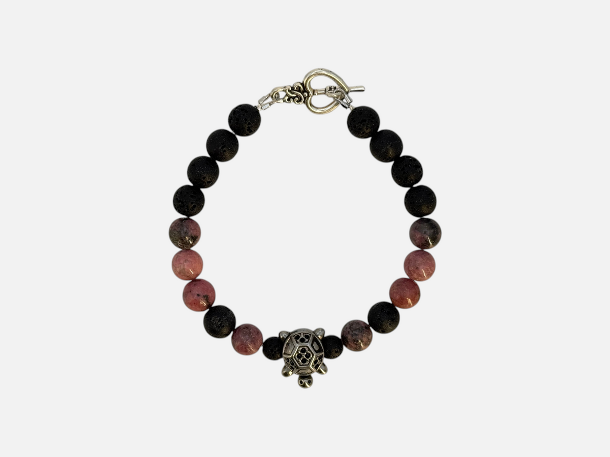 SPARQ kralenarmband met zwarte lavastenen, roze rhodoniet en een zilverkleurige schildpadbedel op witte achtergrond.