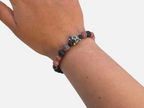 SPARQ kralenarmband met zwarte lavastenen, roze rhodoniet en een zilverkleurige schildpadbedel om een pols.