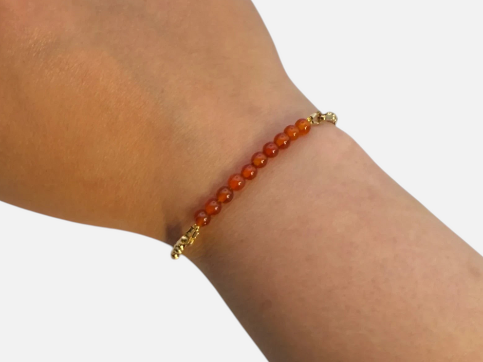 SPARQ armband met oranje edelsteenkralen en een verfijnde goudkleurige schakelketting om een pols