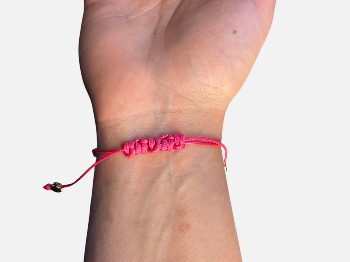 SPARQ roze armband met verstelbare schuifknoop gedragen om een pols voor een zomerse bohemian look.