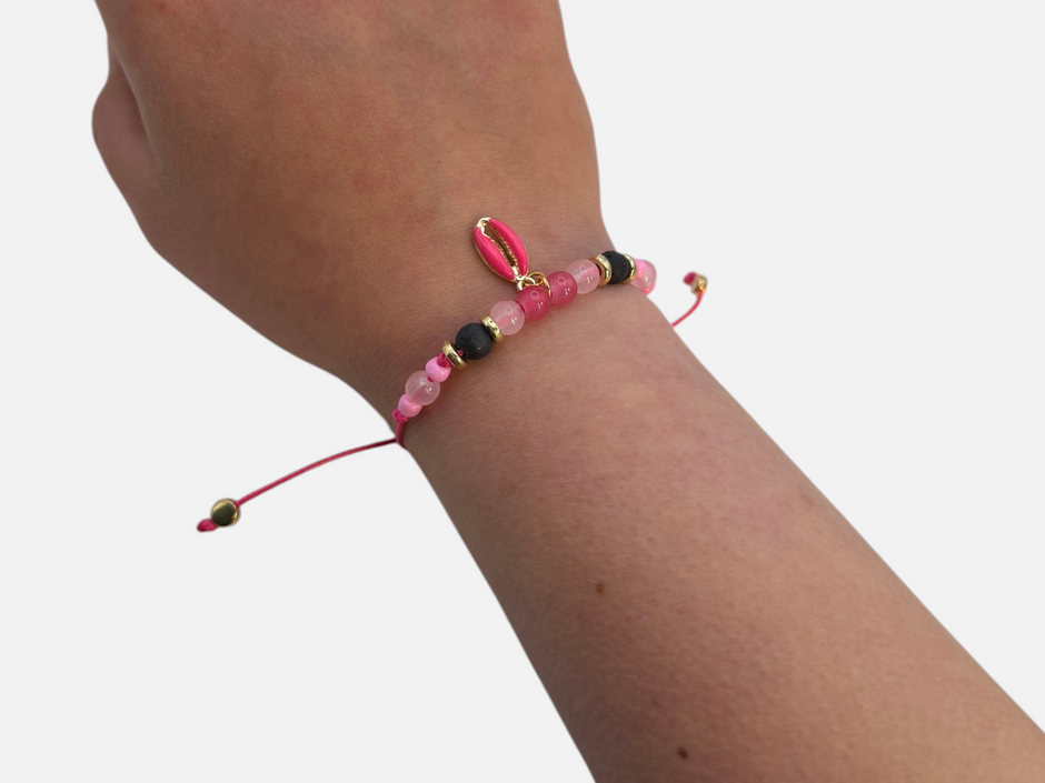 SPARQ handgemaakte roze schelp armband met zwarte kralen en goudkleurige accenten om een pols.
