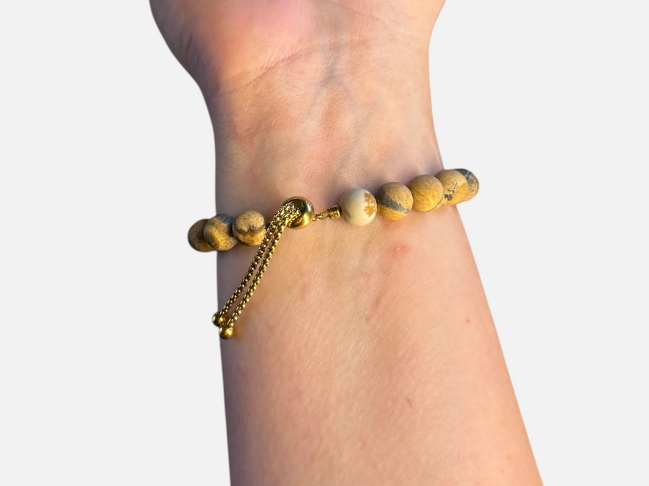 SPARQ verstelbare armband met bruine kralen en gouden klaverbedel om een pols