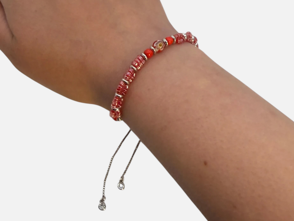 SPARQ verstelbare armband met rode kralen en bloemmotief, gedragen om een pols voor een elegante uitstraling.